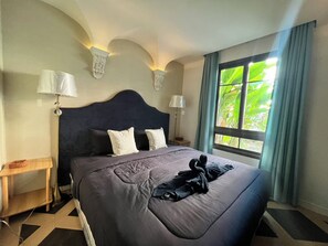 Habitación de hotel con una cama grande, dos lámparas de noche, una ventana con cortinas y un adorno en la pared.