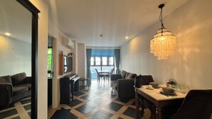 A modern living room with a dining area, a television, and a chandelier.
