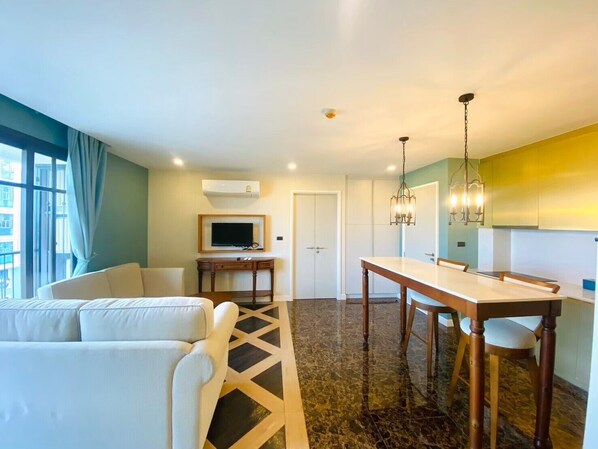 Una habitación de hotel moderna con sofá, mesa de comedor y televisor.