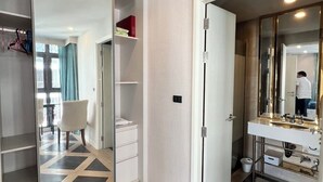 A modern hotel room with a large mirror, a white vanity, and a geometric patterned floor.