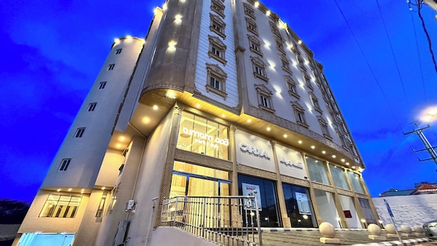 Un hotel de varios pisos con una entrada destacada, señalización iluminada y un diseño arquitectónico moderno.