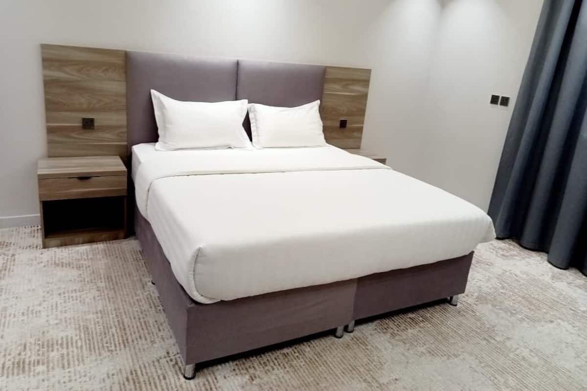Ein modernes Schlafzimmer mit einem Bett, Nachttischen und einem Teppichboden.