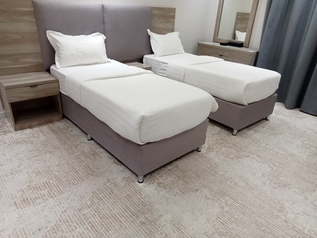 Una cama doble con cabecera, mesita de noche y espejo.