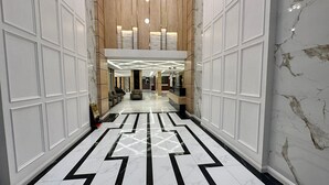 Un vestíbulo de hotel con piso de mármol, área de descanso y una recepción.