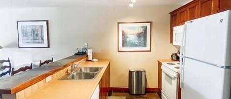 A kitchen with a central island, a stove, a sink, and a refrigerator.