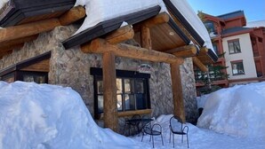 Un bâtiment en pierre avec un porche en bois et une enseigne indiquant un restaurant de pizzas.