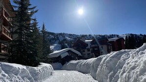 Un paysage enneigé, avec un ciel dégagé, un soleil brillant et des bâtiments en arrière-plan.