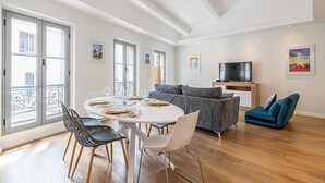 Un salon moderne comprenant un coin repas, de grandes fenêtres et un téléviseur à écran plat.