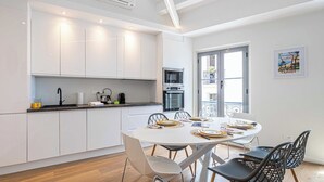 Une cuisine moderne avec des meubles blancs, une table à manger pour quatre personnes et un balcon avec vue.