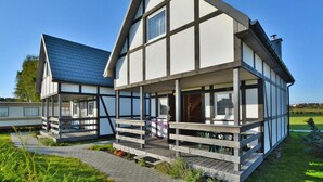 A modern two-story house with a balcony and a covered porch. - Comfortable Holiday Homes With Terraces (Postomino)