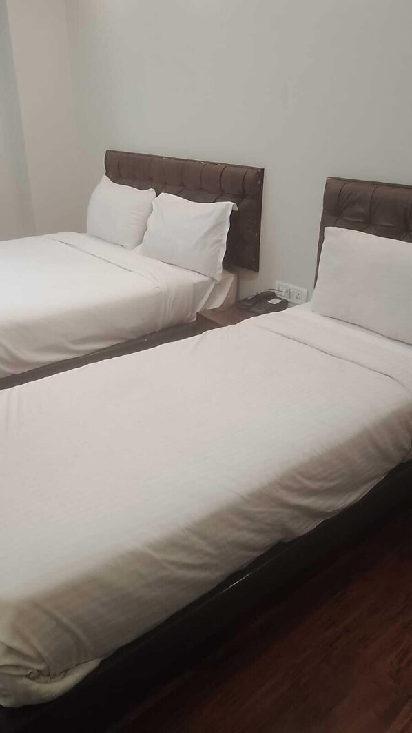 Two single beds with brown headboards in a room.