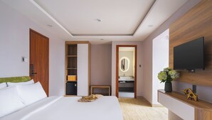 Ein modernes Hotelzimmer mit einem großen Bett, einem Holzschrank, einem an der Wand befestigten Fernseher und einem kleinen Tisch mit einem Blumenstrauß.