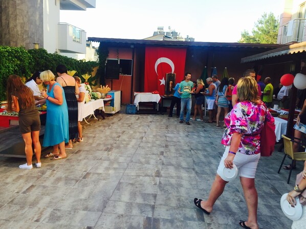 Evento al aire libre con gente de pie alrededor de mesas de comida y bebidas.