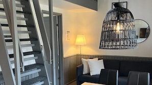 A modern interior with a staircase, a dining area with chairs, a sofa, and a hanging light fixture. - Ystad Camping (Ystad)