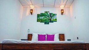 Ein Schlafzimmer mit einem hölzernen Bett, weißer Bettwäsche, zwei Wandleuchten und einer Gruppe von drei gerahmten Landschaftsbildern.