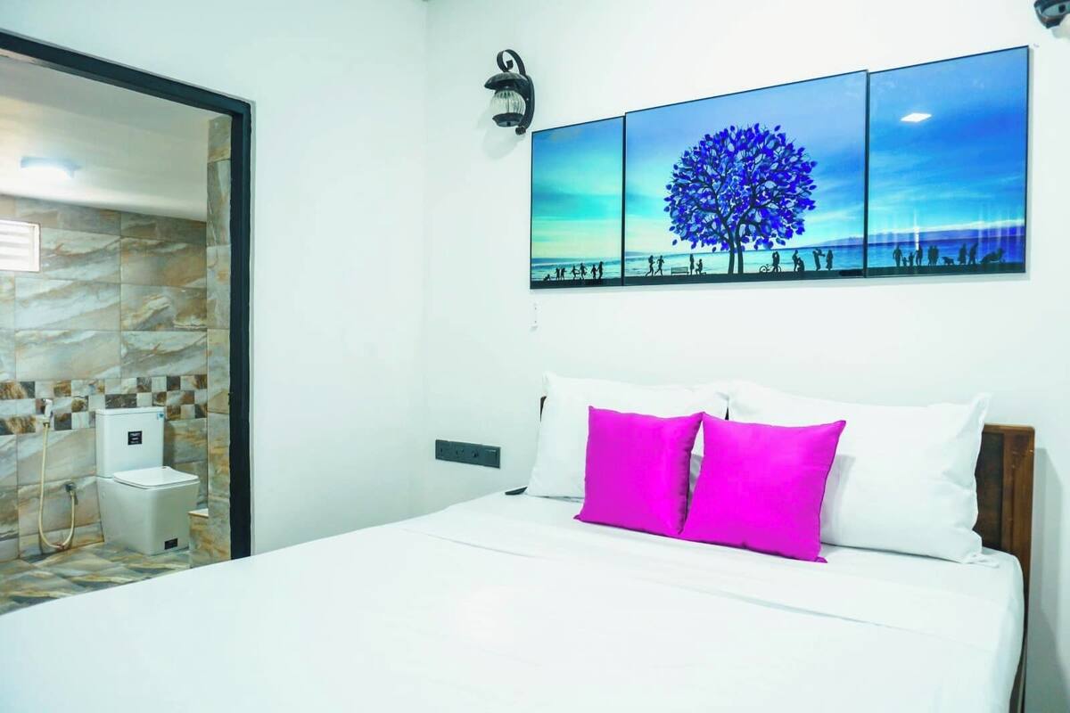 Ein Hotelzimmer mit einem Bett, einem Nachttisch, einer Wandlampe und einem großen Fenster.