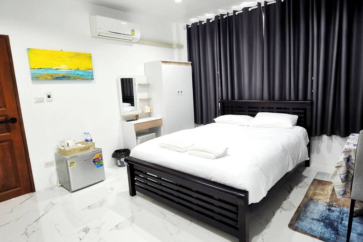 Ein Hotelzimmer mit Bett, Schreibtisch, Stuhl, Kleiderschrank und einem Bild an der Wand.