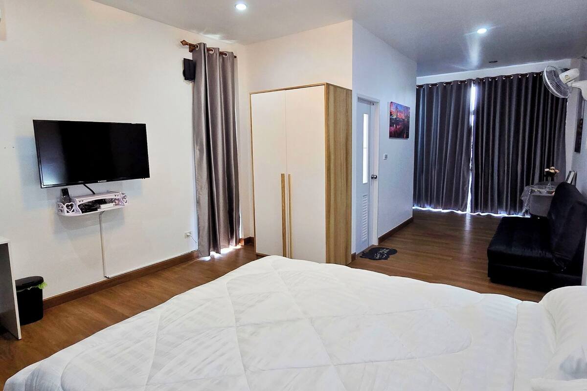 Ein Hotelzimmer mit Bett, Schreibtisch mit Stuhl, Fernseher, Kleiderschrank und einem Badezimmer mit Duschvorhang.
