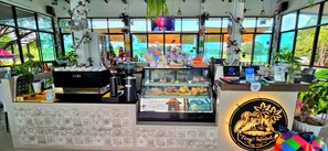 A coffee shop interior with a counter, display case, and various coffee-making equipment. - Tiny Island Lake Lodge (Bangkok)