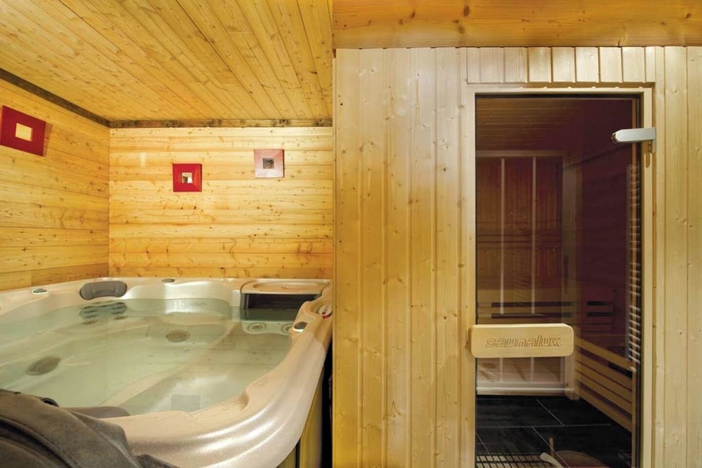 Un cuarto de sauna con paredes de madera y una puerta de vidrio que da a una zona de ducha.