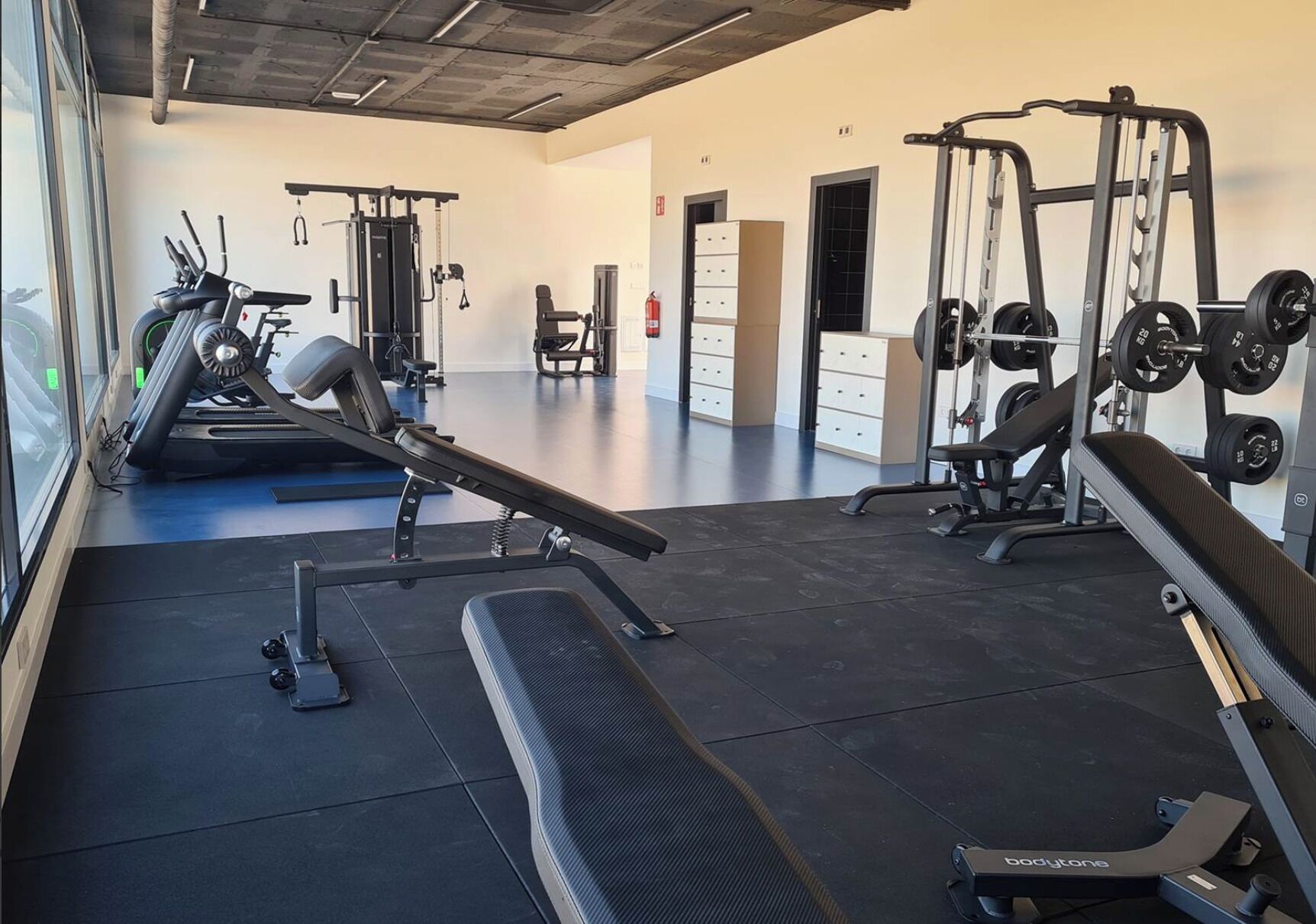 A gym with treadmills, weight benches, and a squat rack.