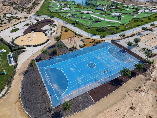 Vista aérea de un complejo deportivo con cancha de baloncesto, canchas de tenis y campo de golf.