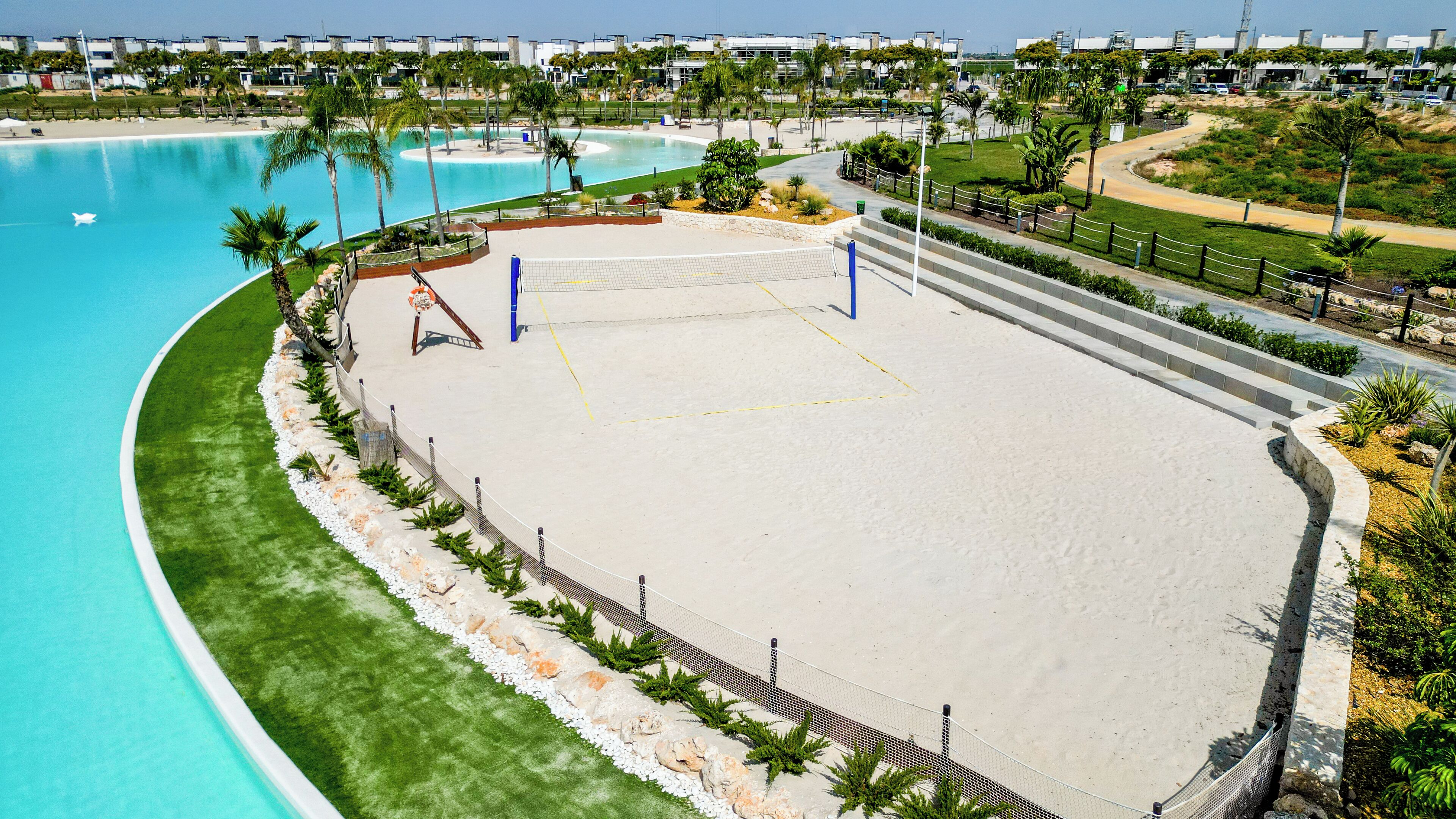 Un campo da pallavolo sulla spiaggia, con una rete, circondato da una recinzione e vicino a una piscina.