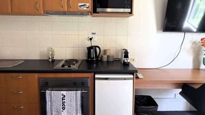 A compact kitchen with wooden cabinets, a microwave, a toaster, and a dishwasher.