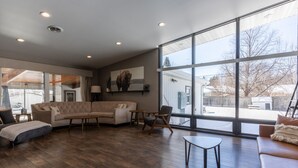 A spacious living room with a large window, a sofa, a coffee table, and a chair. - Historic home w/ indoor pool on Iconic 8th St (Fargo)
