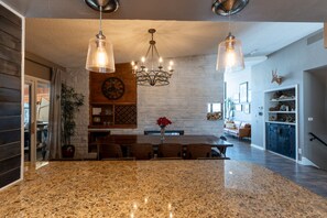 A spacious kitchen with granite countertops, a central island, and pendant lighting.