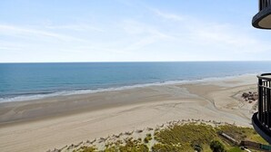 Une vue sur la plage depuis un balcon, avec un ciel dégagé.
