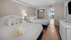 Une chambre d’hôtel avec deux lits, un bureau, une lampe, un téléphone et une télévision.