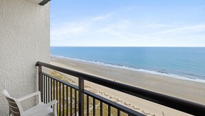 Un balcon avec vue sur une plage et l’océan.