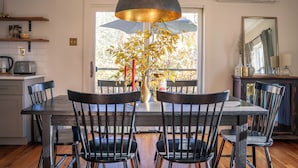 A dining area with a table, chairs, a vase with flowers, and a pendant light.