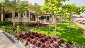 A modern house with a well-maintained garden, including a lawn and various plants. - Palm Jumeirah, Studio, Fantastic sea, beach and skyline view, Beach  (Dubai)