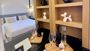 A hotel room with a bed, a minibar, and a wooden shelf with decorative items. - Palm Jumeirah, Studio, Fantastic sea, beach and skyline view, Beach  (Dubai)