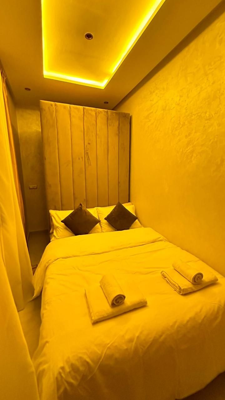 Una habitación de hotel con cama, almohadas y una lámpara en el techo.