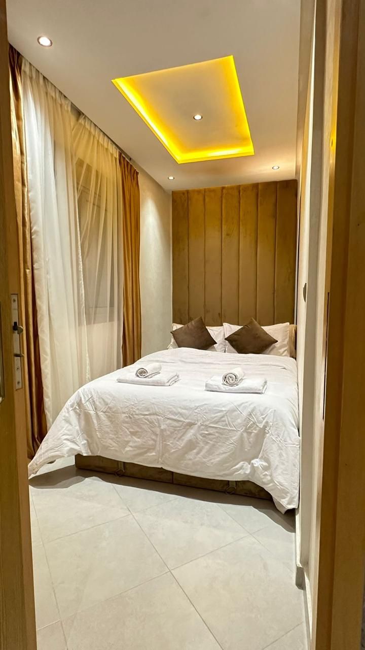 A hotel room with a bed, a ceiling light, and a curtain.