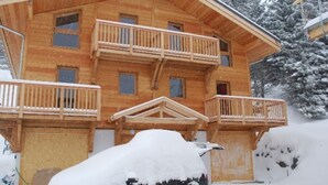 A wooden cabin with a balcony and a car covered in snow. - Attached chalet for 8 on 3 levels, pets allowed (Chamrousse)