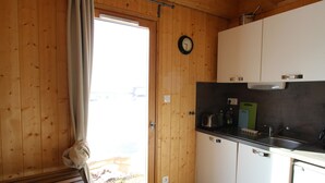 A wooden interior with a kitchen area, including cabinets, a sink, and a window with curtains. - Attached chalet for 8 on 3 levels, pets allowed (Chamrousse)