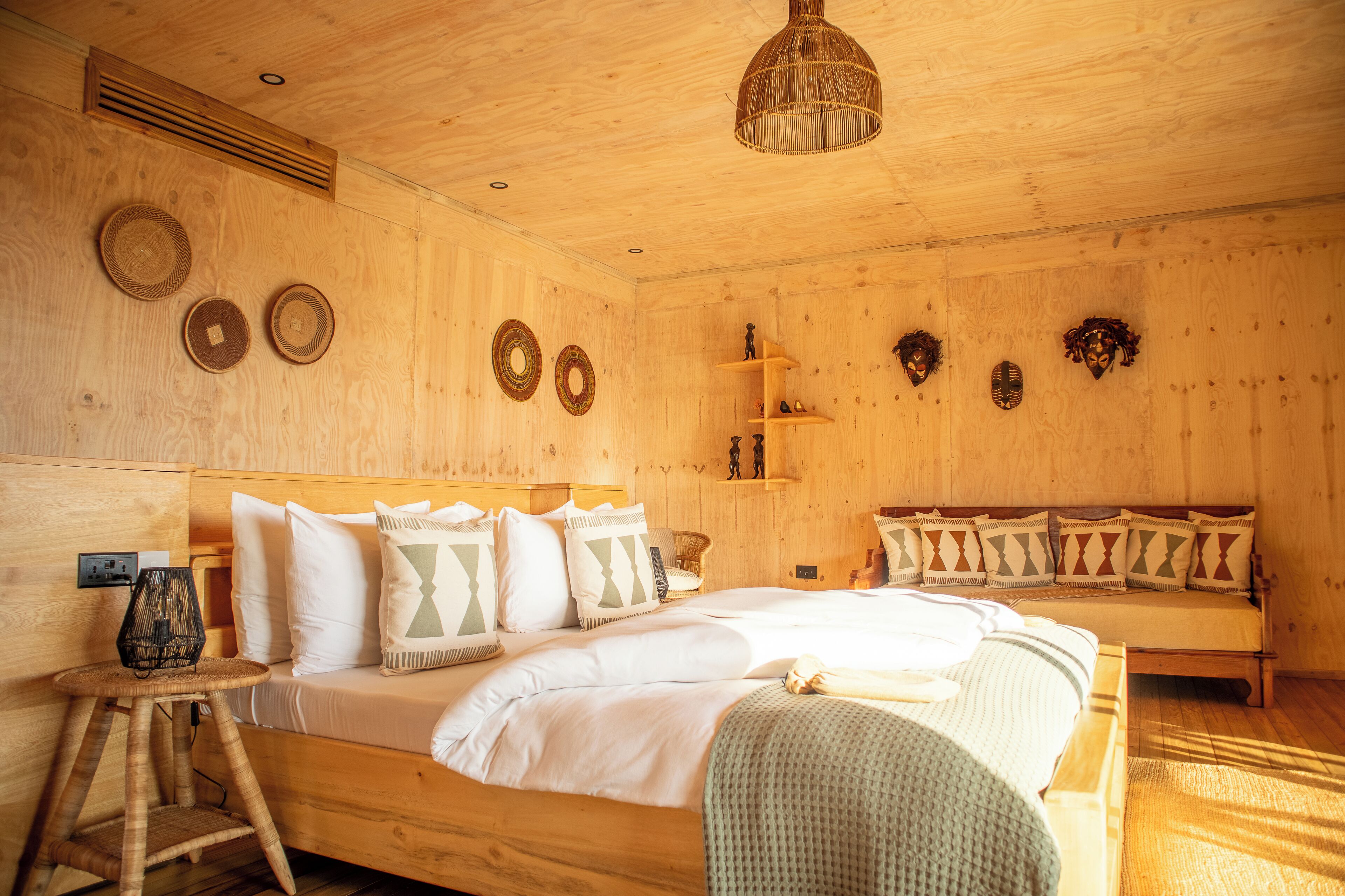 Una habitación de madera con una cama, un banco y adornos en las paredes.