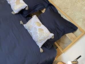Un llit amb llençols blau fosc i almoines decorades amb motius d'full d'or.