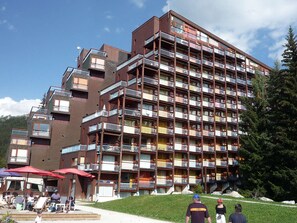 A multi-story hotel with balconies, a pool area with umbrellas, and a view of the mountains. - Ski-in Studio 4 pers, Arc 1800 (Les Arcs 1800)