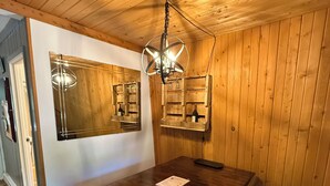 A dining area with a wooden table, chairs, a chandelier, and wooden walls. - Charming Chalet in Powderhorn Village (Bessemer)