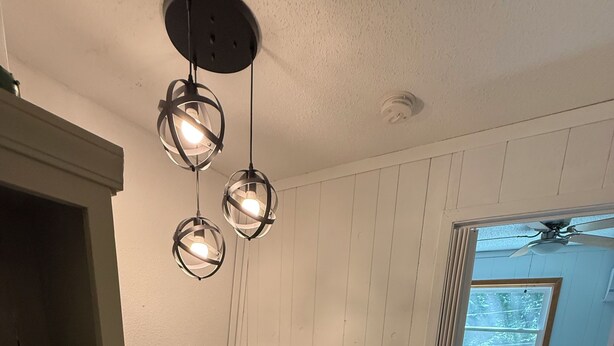 A room with a wooden staircase, a white wall with a window, and a ceiling fan. - Charming Chalet in Powderhorn Village (Bessemer)