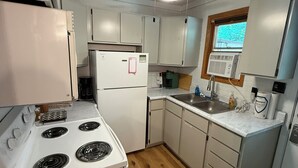 A compact kitchen with white appliances, a wooden floor, and a ceiling fan. - Charming Chalet in Powderhorn Village (Bessemer)