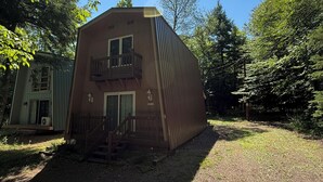 A two-story building with a balcony, surrounded by trees and a gravel driveway. - Charming Chalet in Powderhorn Village (Bessemer)