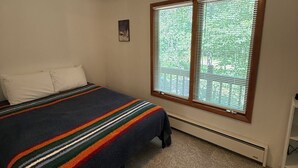 A bedroom with a bed, a ceiling fan, a window with blinds, and a radiator. - Charming Chalet in Powderhorn Village (Bessemer)