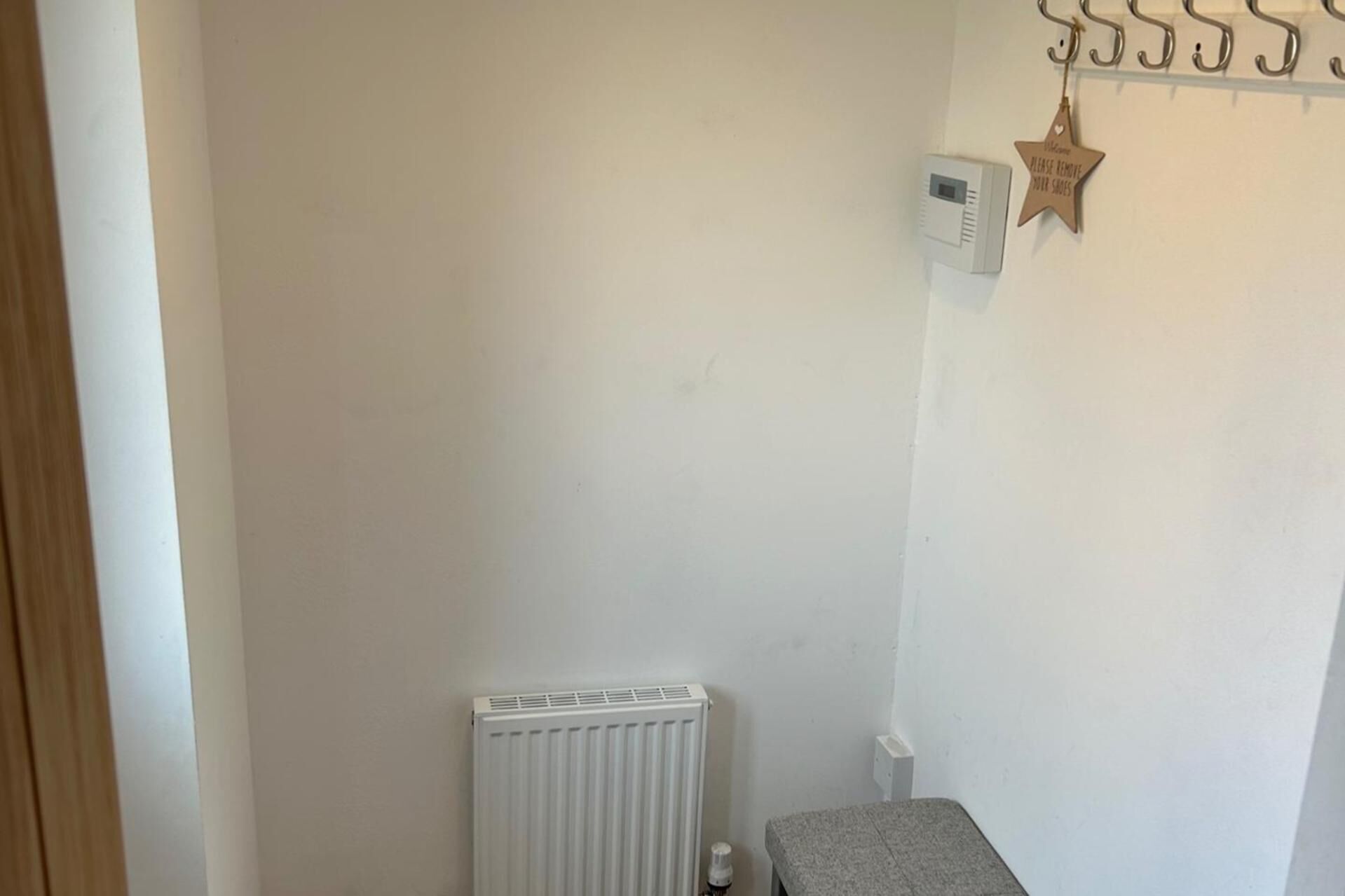 A small, sparsely furnished room with a white radiator, a small table, and a wall-mounted air conditioning unit.