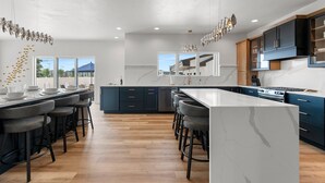Una cocina moderna con una isla central, taburetes de bar y un ventanal grande.